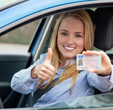 A woman in the drivers seat of her car holding up an id.